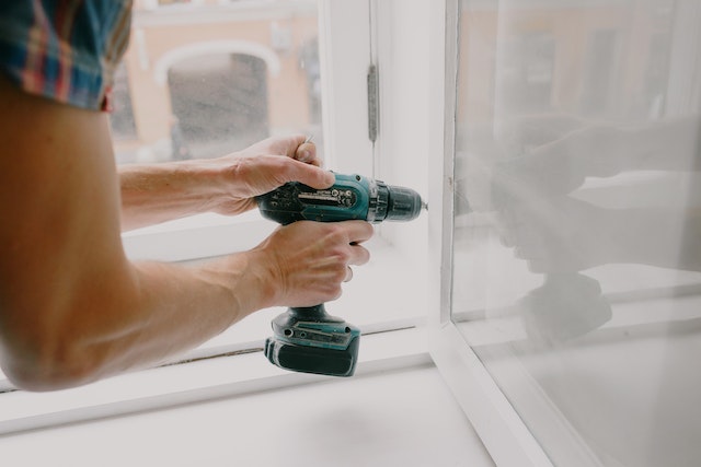 Close up of someone using a drill to fix part of a window